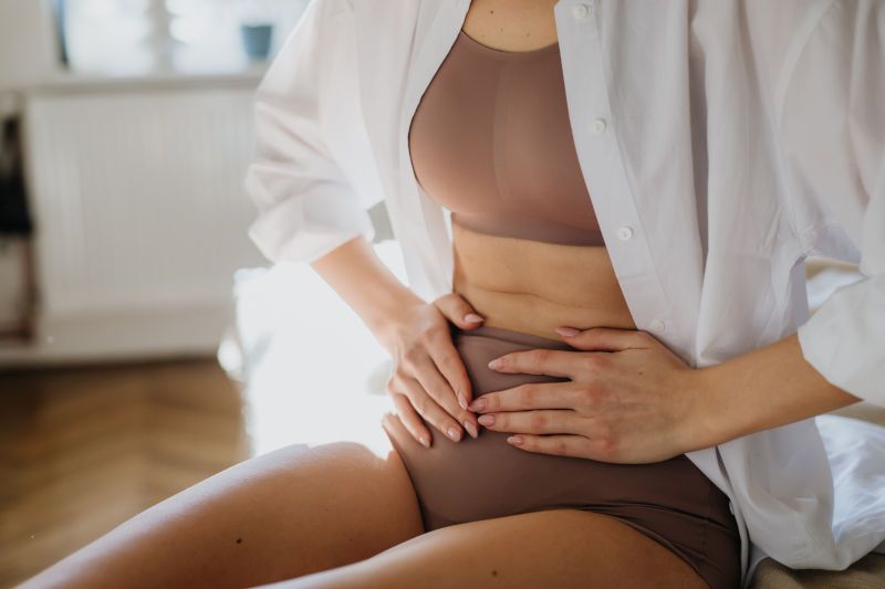 Woman holding her stomach, experiencing cramping
