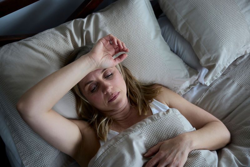 Woman with her head on her forehead in bed