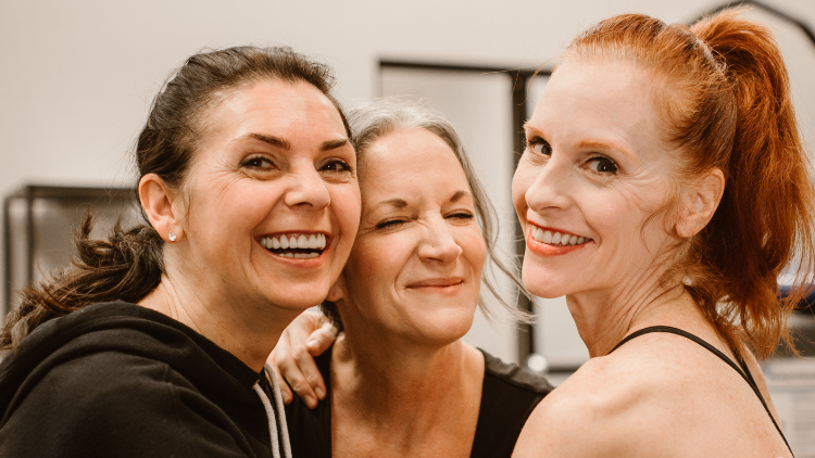 Three menopausal women embrace each other.