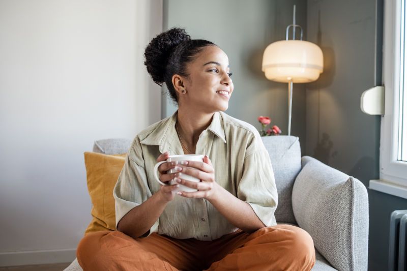 Woman holding a cup of tea looking happily to her left