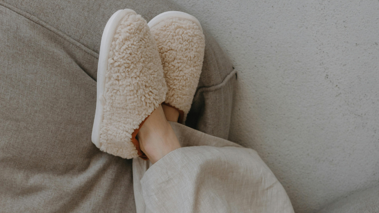 Legs rest propped up, ankles crossed, in fuzzy slippers.