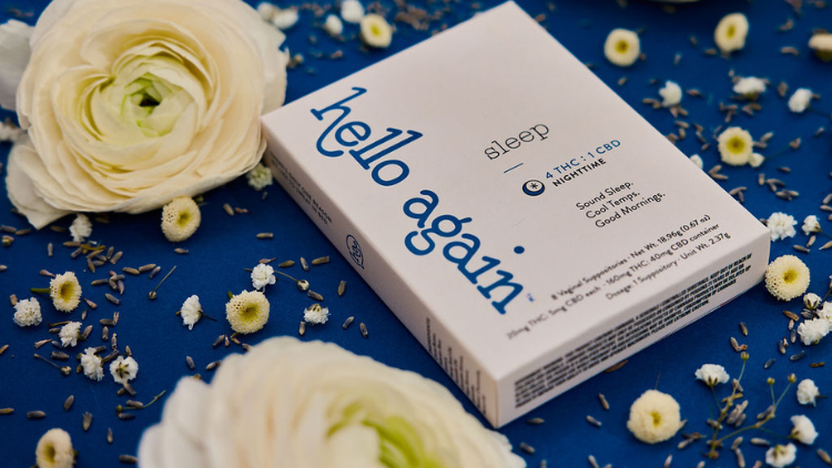 The Sleep product from Hello Again lays on a dark blue background with white and yellow flowers surrounding it.