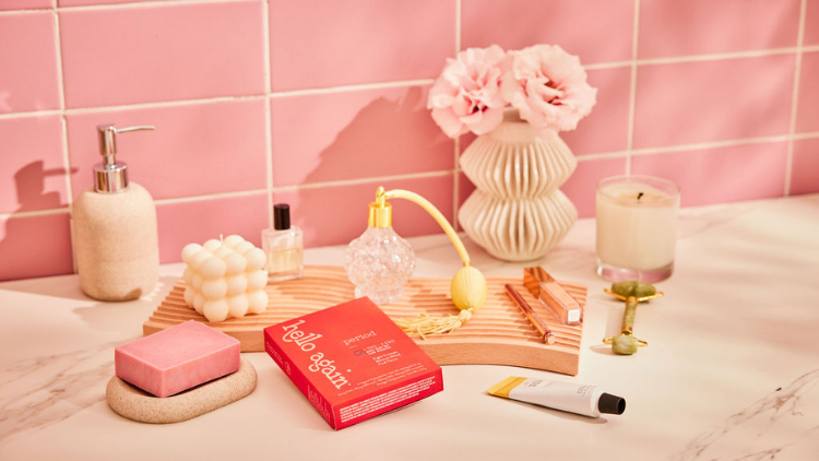 Period from Hello Again sits on a bathroom countertop with soap, perfume, and other bathroom items and decorations.