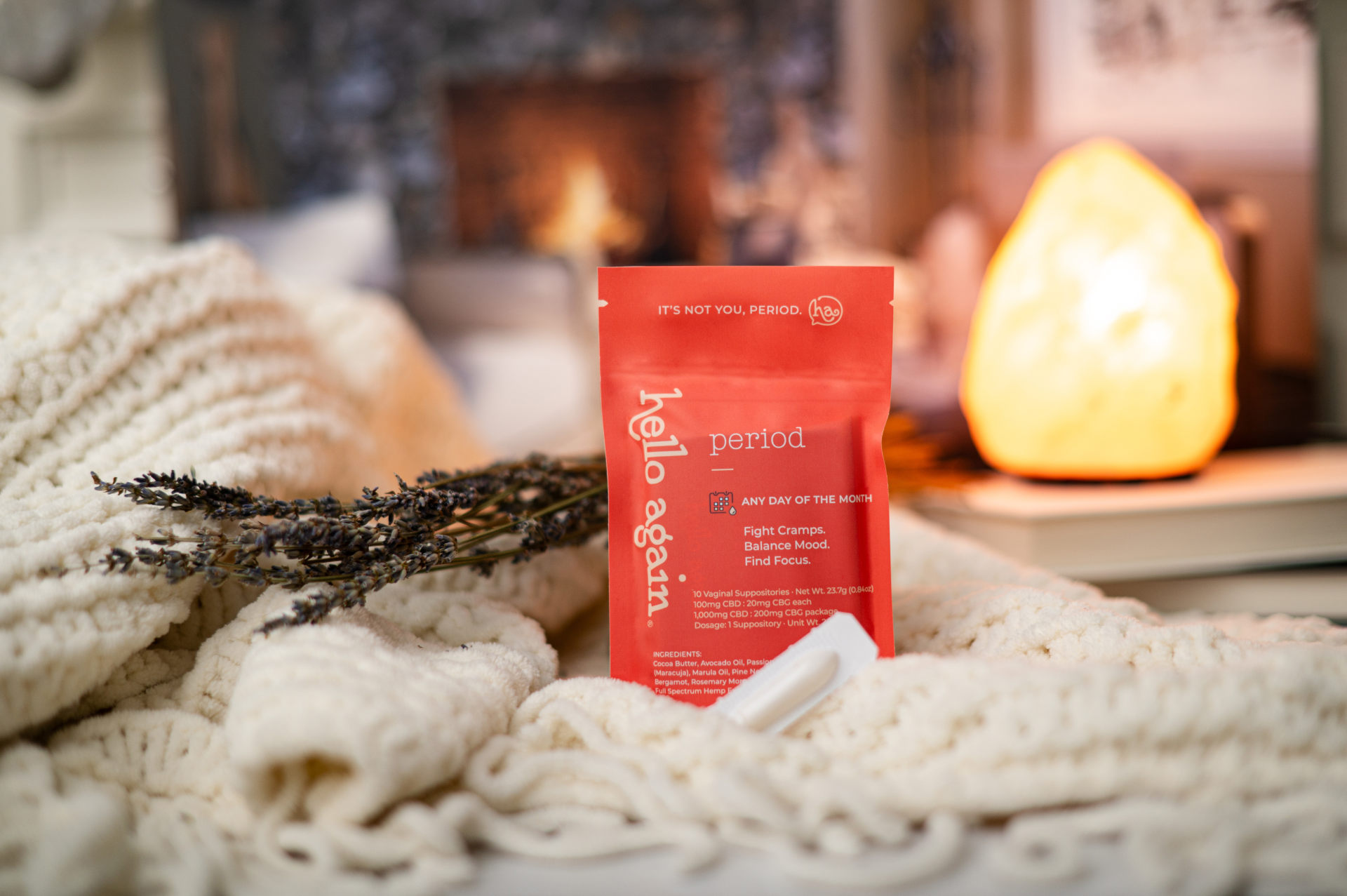 Hello Again Period Product sitting on a bed with a blanket with a salt lamp behind