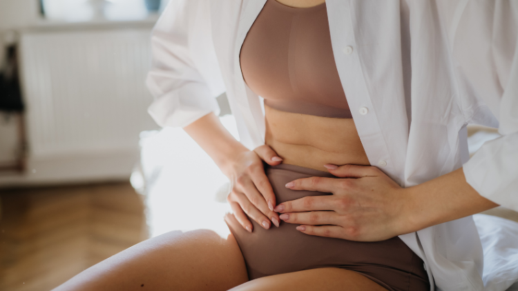 A woman holds her abdomen, her body tense with period pain.