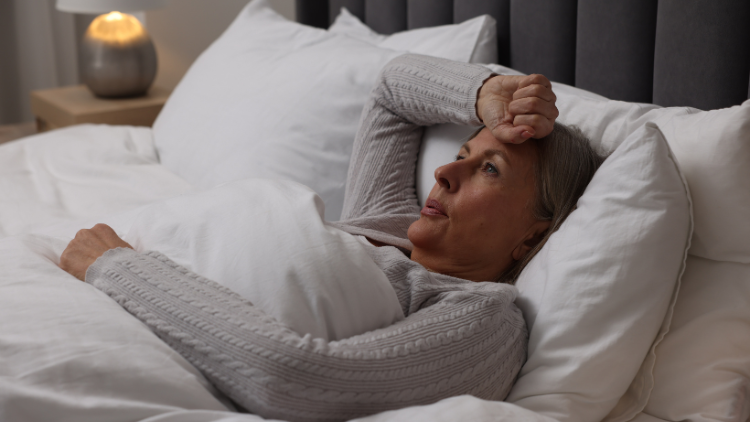 A woman lies awake in bed with Sleep and Menopause symptoms.