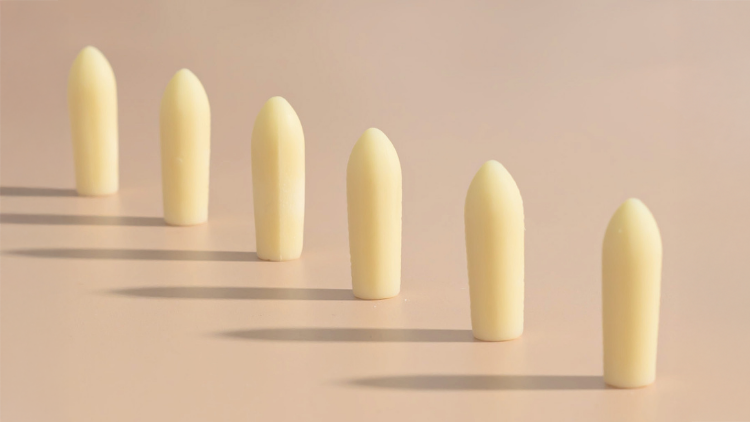 A row of vaginal suppositories arranged on a neutral background, illustrating how to use a suppository as part of a simple, step-by-step routine.