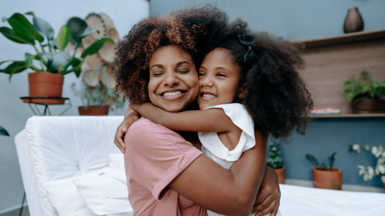 Smiling mother hugging her daughter in a cozy living room, capturing the warmth and strength of a modern matriarch.