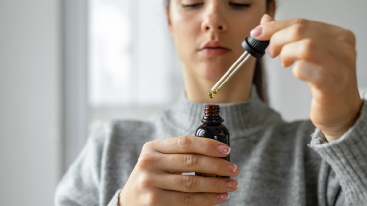 Person using a CBD tincture as part of a consistent CBD wellness routine.