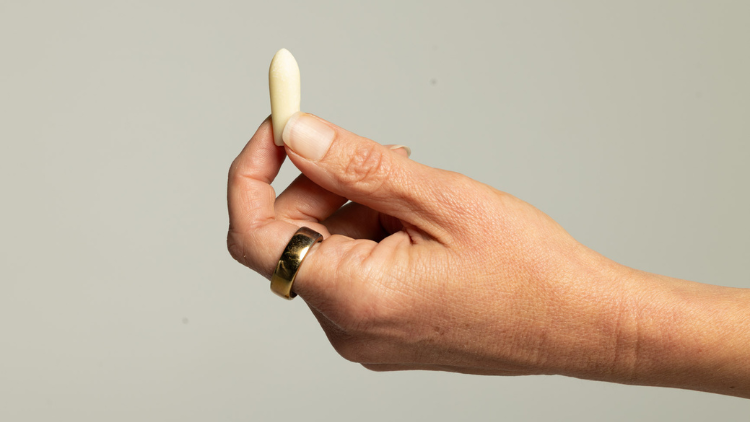 Hand holding a Hello Again CBD suppository for a CBD wellness routine.