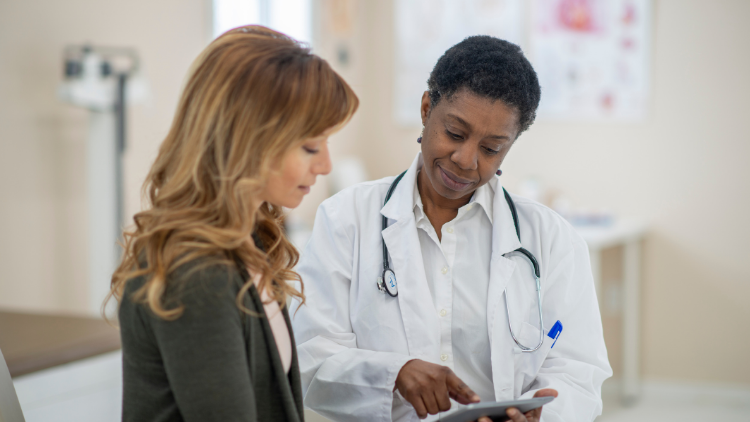Woman in her 40s discussing women's health questions with her doctor during a routine wellness appointment.
