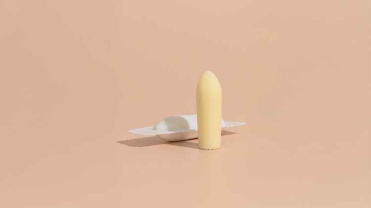 CBD suppository standing upright beside its opened individual wrapper.