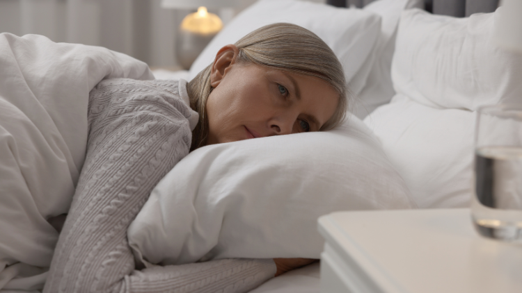 Middle-aged woman lying awake in bed, illustrating sleep disturbances commonly experienced during menopause.