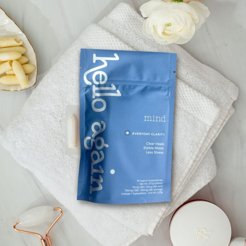 Hello Again MIND suppository product on display on a countertop with a towel, roller, flower next to it
